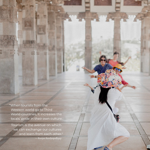 A line of three tourists doing the "happy pose" for a photo. They're in an ornate white temple. The quote on the photo reads, "When tourists from the Western world go to Third World countries, it increases the locals’ pride in their own culture. Tourism is the avenue on which we can exchange our cultures and learn from each other." by Ranjan Bandyopadhyay.
