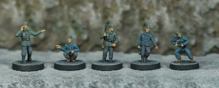 a set of five wargame miniatures. German world war two soldiers and mechanics. Two wear military grey-green tunics and grey trousers and the others wear dark blue jackets and boilersuits.