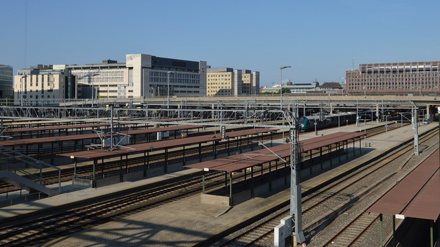 A photo of train tracks alternating with platforms each with a metal roofed structure.