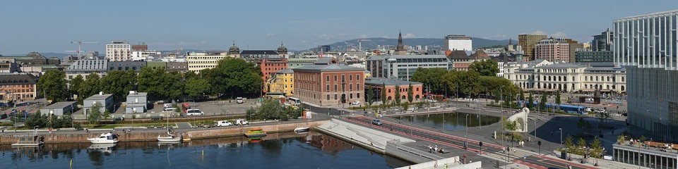 A panoramic photo of downtown Oslo with a bay in the foreground and hills visible in the distance.