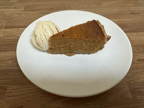 Photograph of a slice of pumpkin pie on a plate with a scoop of vanilla ice cream