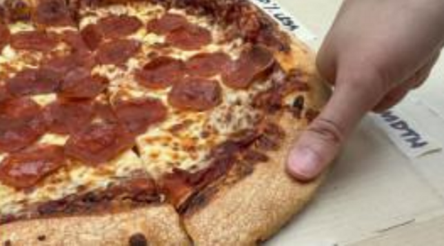 Somebody putting their thumb on the crust of a pepperoni pizza, as directed