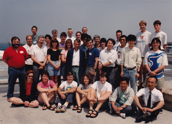 A group of people gathered outside near the ocean for a picture.