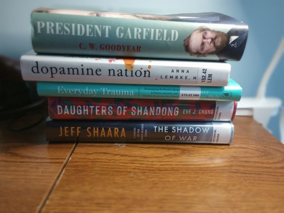 A stack of five books laying on their backs with the spines showing. 