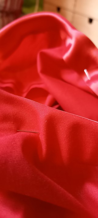 Photo shows the red outside fabric, with pins holding the red satin bias fabric to the inside.