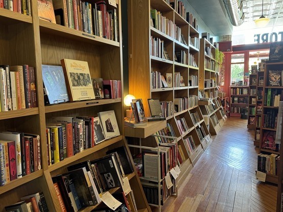Various bookshelves up against a wall in a book store filled with books. 