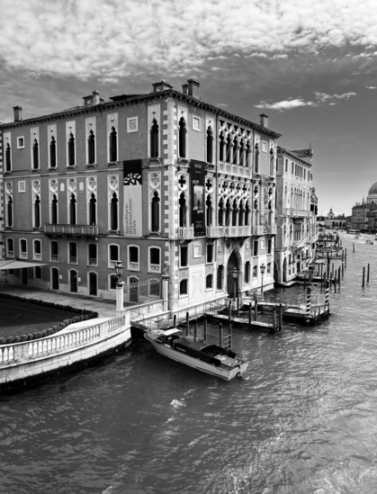 Black and white photo of the Palazzo Cavalli-Franchetti in Venice, with the water and boats moored outside.
