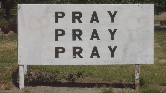 A black and white sign reading 
          PRAY
          PRAY
          PRAY