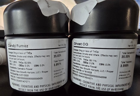 Two black 1/8 jars of cannabis with white labels. Candy Fumez (35.03% THC / 3.897 Terps) on the left and Ghost OG (35.55% THC / 3.598% Terps) on the right