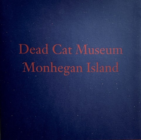 A softcover book with a dark blue background. Red letters of the title spell out two titles: 'Dead Cat Museum' and 'Monhegan Island'. Both are names of paintings by American artist Jamie Wyeth. The book is an exhibition catalog for a 1999 show of works by this artist at the gallery of James Graham & Sons in New York City. 
