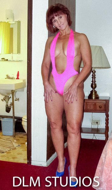 MILF in a pink tankini and blue hi heels posing hands on thighs before the bondage begins.