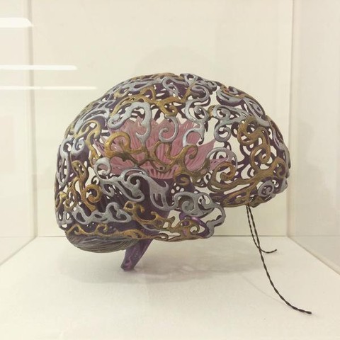A brain-shaped metal sculpture with intricate gold and silver patterns