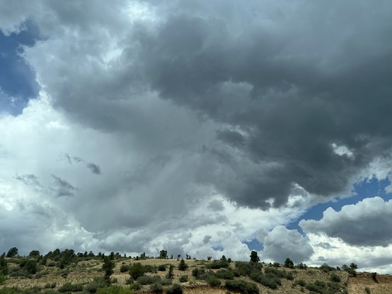Dark clouds form over a high desert landscape.