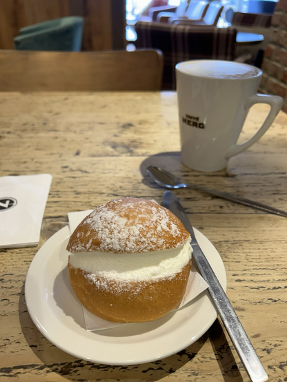 A mug of coffee and a maritozzo bun at the coffee shop.