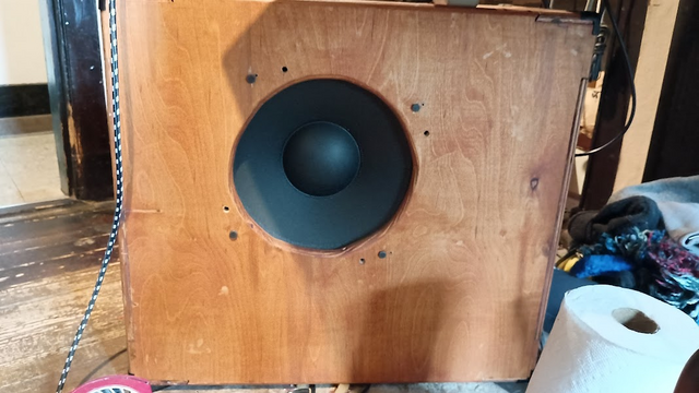 12 inch speaker with a 3 inch center dome sits in my home-made bass cabinet, looking like an iris and pupil staring out of a cube of cheese.
The old bolt-holes show about 10 degrees clockwise of the new bolts.
The wood is pine plywood, stained orange - Minwax pecan.