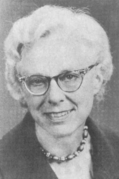 Anna Scholl Espenschade later in life, a smiling older white woman with white wavy hair, wearing glasses and a bead necklace with a dark jacket