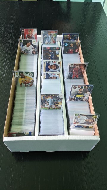 A 3,000-ct box full of sleeved soccer cards on a dark chocolate dinner table.

A few cards are pulled up to show the sets included in it.