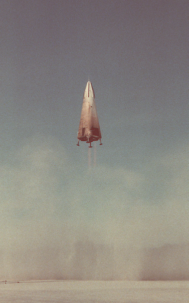 Lift-off of the DC-X3, a pyramid-shaped vehicle with four landing legs and a single rocket engine designed to carry a payload to earth orbit and land again.