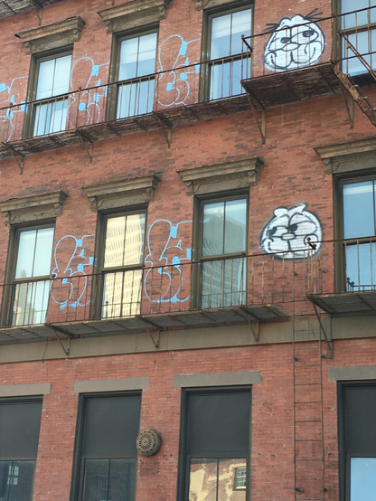 Red brick facade and windows with graffiti, including a sky cat 
