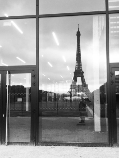 a black & white image of the #EiffelTower reflecting in the glass windows of the arena champs de mars 