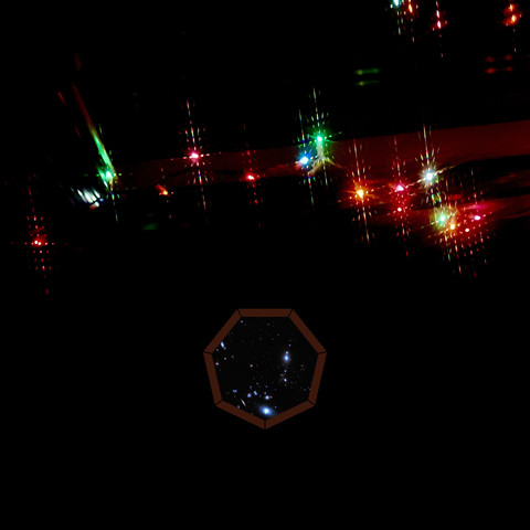 The cover of On Idyl's second full length album, Mycorrhiza / Miyake - featuring blurry Christmas lights and a tiny cosmos within a heptagon.