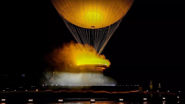 an image of the OlympicFlame in Paris in the evening, which  is a montgolfiere hot air balloon, carrying a so-called ring of fire 