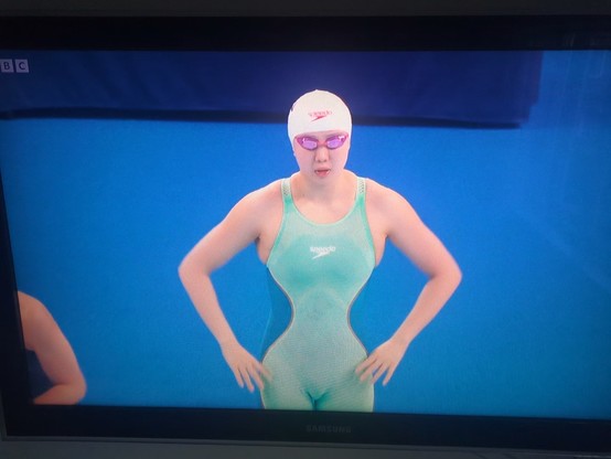 Photo of Chinese swimmer, Tang Qianting, wearing a swimsuit that is the same colour as the background wall making it look as if she's got a 10 inch waist.