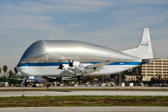 Aero Spacelines Super Guppy N941NA about to land like a giant aluminum guppy with a blue stripe and tiny eyes.