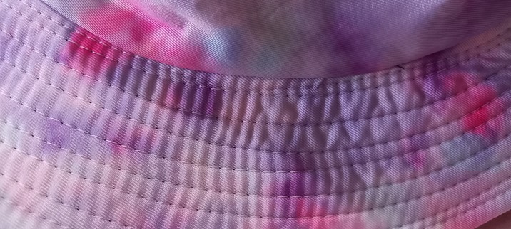Photo shows the purple marbled bucket hat that is my sunhat this year, zoomed in on the uneven topstitching which is indeed most wonky.