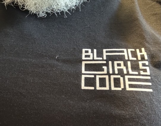 Black girls code in white on upper left of black t shirt.