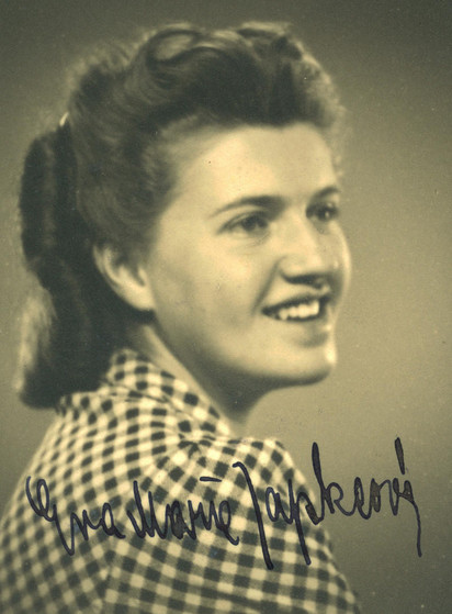 Vintage sepia photograph of a smiling woman with styled hair, wearing a checkered shirt.