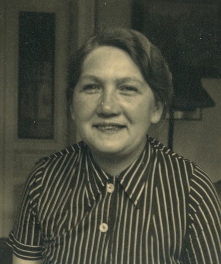Portrait of a woman, smiling and wearing a striped shirt.
