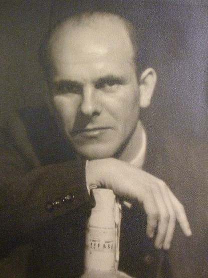 Black-and-white portrait of Adam Kopyciński, posing with his hand on his wrist, looking serious.
