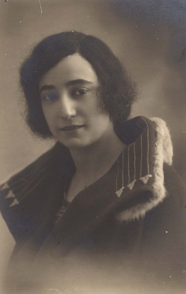 Vintage portrait of a woman with bobbed hair, wearing a dark coat with a fur collar, providing a classic representation of early 20th-century fashion.
