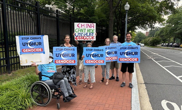 Photo of seven people on the sidewalk outside the Chinese embassy in Washington DC. Six are holding signs saying 