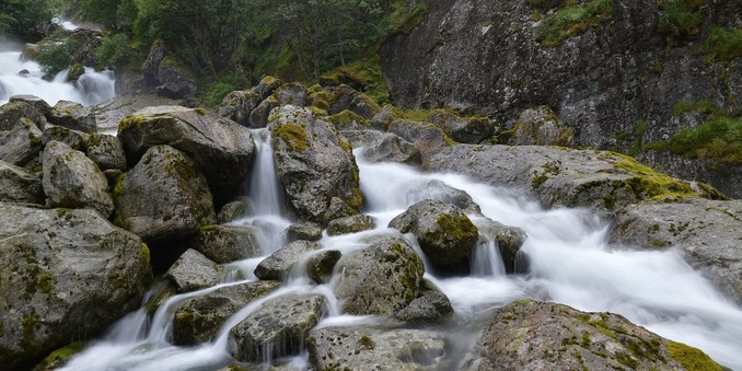 A long exposure photo of a waterfall flowing over rocks. 