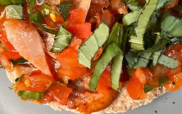 Chopped bacon, tomato and basil on brown bread.