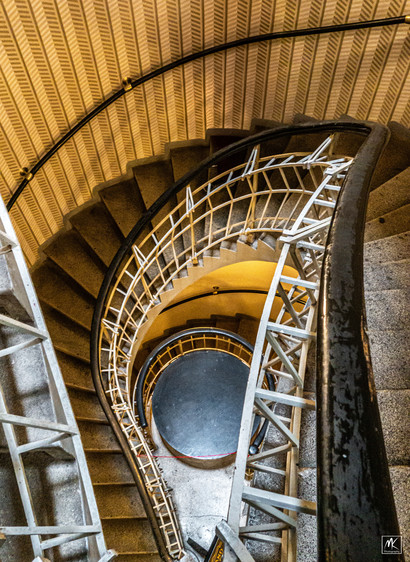 Color photo looking down multiple floors in an asymmetrical interior stairway. 