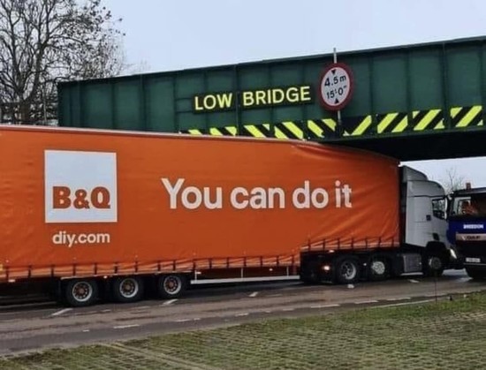 Large red B&Q lorry stuck under a low bridge, and the logo on the side says You can do it.