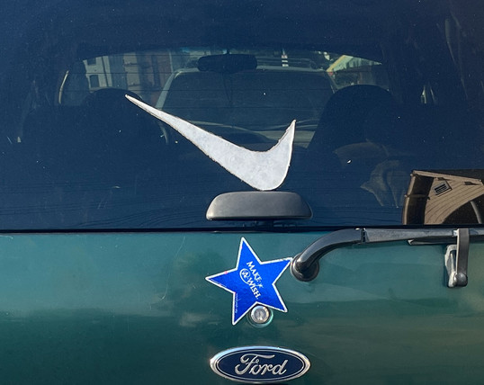 The back window of an SUV with a Nike Swoosh decal, applied backwards.