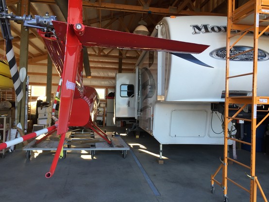 Close-up photo of a garage space containing a Robinson R 44 helicopter on a rolling platform and a Montana mountaineer fifth wheel trailer, side-by-side. The garage space is 48 feet deep and 28 feet wide.

This photo copyright 2024 by Maria Langer. All rights reserved. Neither this image nor the accompanying alt text may be used to train AI systems.