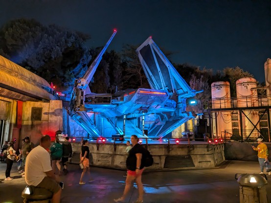 A spaceship on a landing pad is lit up at night 