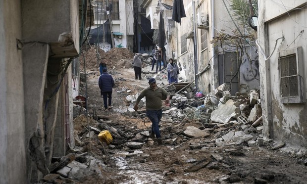 Unos palestinos caminan por las calles destrozadas del campo de Nur Shams tras una incursión de Israel, el pasado 27 de diciembre. (Majdi Mohammed / Getty)