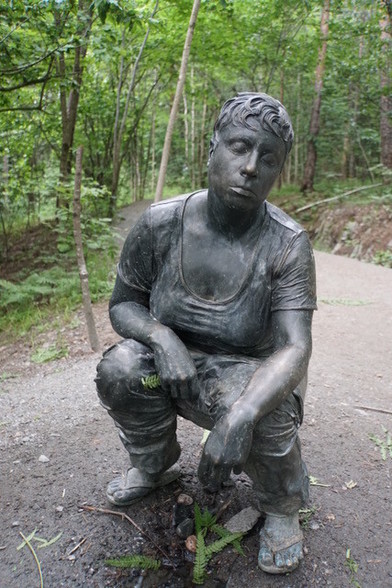 Skulptur einer hockenden Frau die pullert