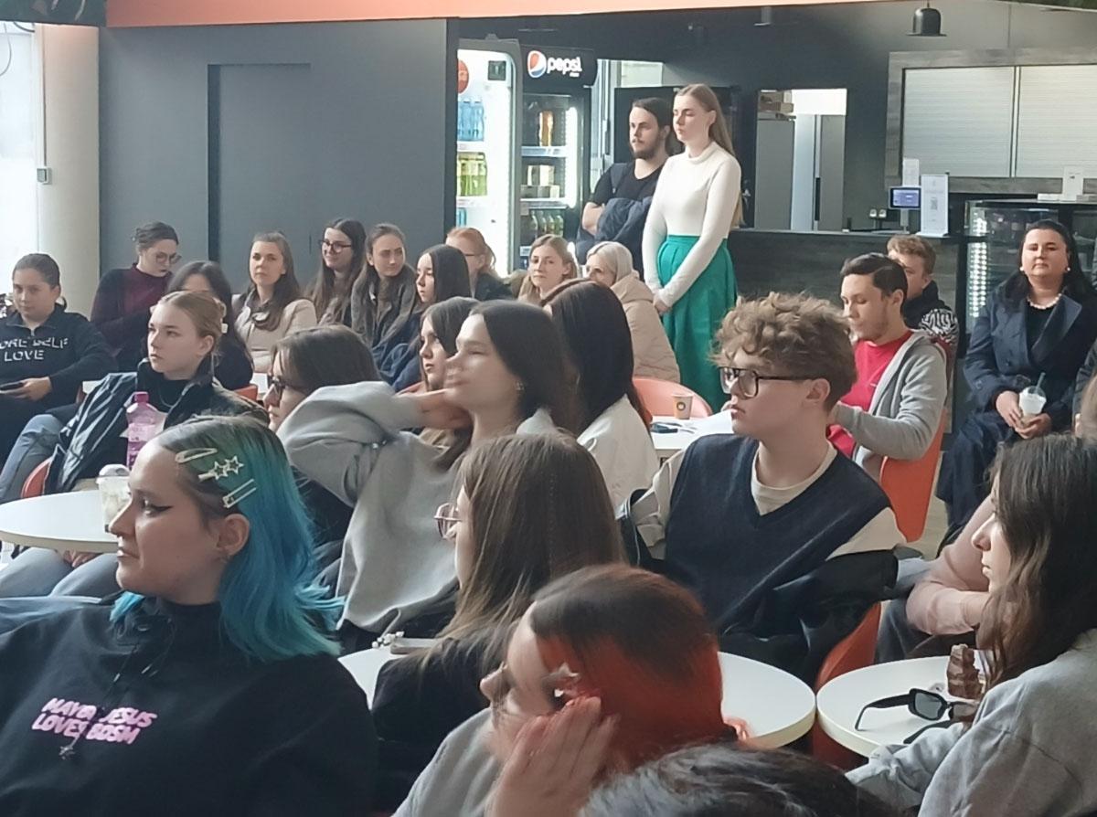 A young audience (people in their 20s) is keenly listening in a university space.