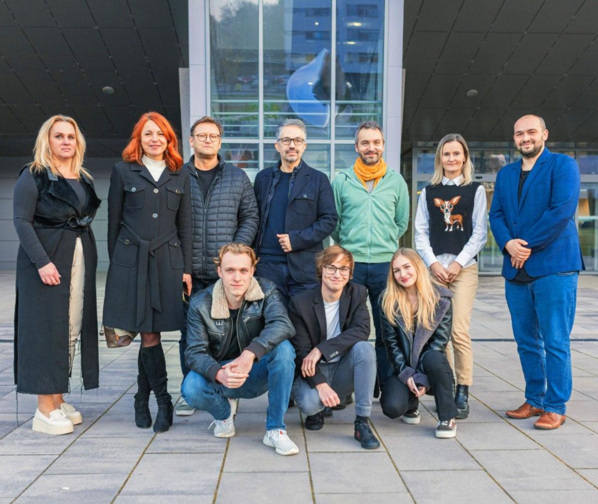 A group photo of 10 people taken in front of a university building.
