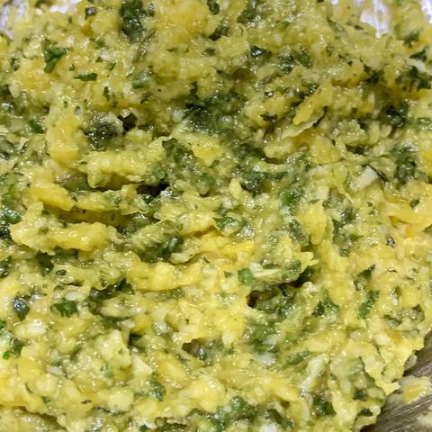 A close-up view of a vibrant, textured mixture featuring yellow and green elements. The overall appearance is chunky and blended.