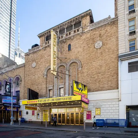 The image shows the exterior of a theater building named the "Golden Theatre." It features a marquee with signage indicating a current production. The architecture appears to be a mix of classic and contemporary styles, typical of theaters in urban areas. The surrounding streets suggest a bustling environment, possibly in a city known for its theatrical performances.

Image Credits: Wikimedia / ajay_suresh / CC BY 2.0