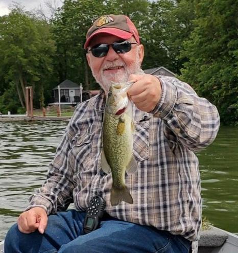 Some guy holding a largemouth bass while sittin in a boat.