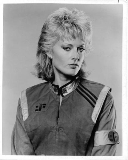 Portrait of Lydia (actress June Chadwick) from the classic "V" TV series from the 80's. She's looking at the camera with a mix of sexy and inquiring look on her face and wearing the "Visitor" uniform. / Retrat de Lydia (actriu June Chadwick) de la clàssica sèrie de televisió "V" dels anys 80. Està mirant la càmera amb una barreja sexy i indagant a la mirada i duu l'uniforme de "Visitant".
